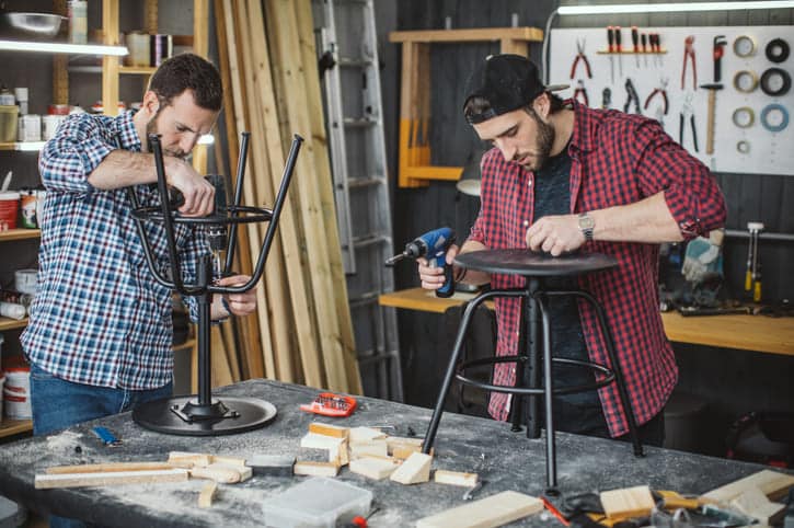 Zwei junge Männer reparieren Stühle in einer Werkstatt